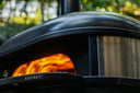 Close-up of an Off Black Gozney Dome XL Gen 2 with bright flames inside its mouth.