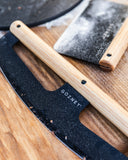 Gozney wooden-handled dough cutter and Pizza Rocker on a flour-dusted wooden worktop