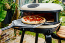 A cooked pepperoni pizza on a placement peel at the mouth of a Bone Gozney Arc XL.