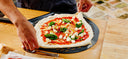 Pizza being topped on a Gozney Balance Placement Peel