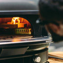 Gozney Dome and Dome XL Wood-Fire Control Kit wood rack in use inside a Off Black Dome Gen 2, with burning wood and flames