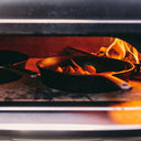 Cast iron skillets cooking beside a wood fire inside a Gozney Dome XL Gen 2