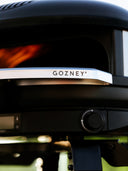 Close-up of an Off Black Gozney Arc XL with a silver Arc XL Mantel and a lit flame
