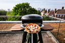 Pizza on a peel beside an Off Black Gozney Arc XL with an Arc XL Mantel on a rooftop terrace