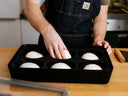 Person placing pizza dough balls into a Gozney dough tray with a six-compartment silicone insert.